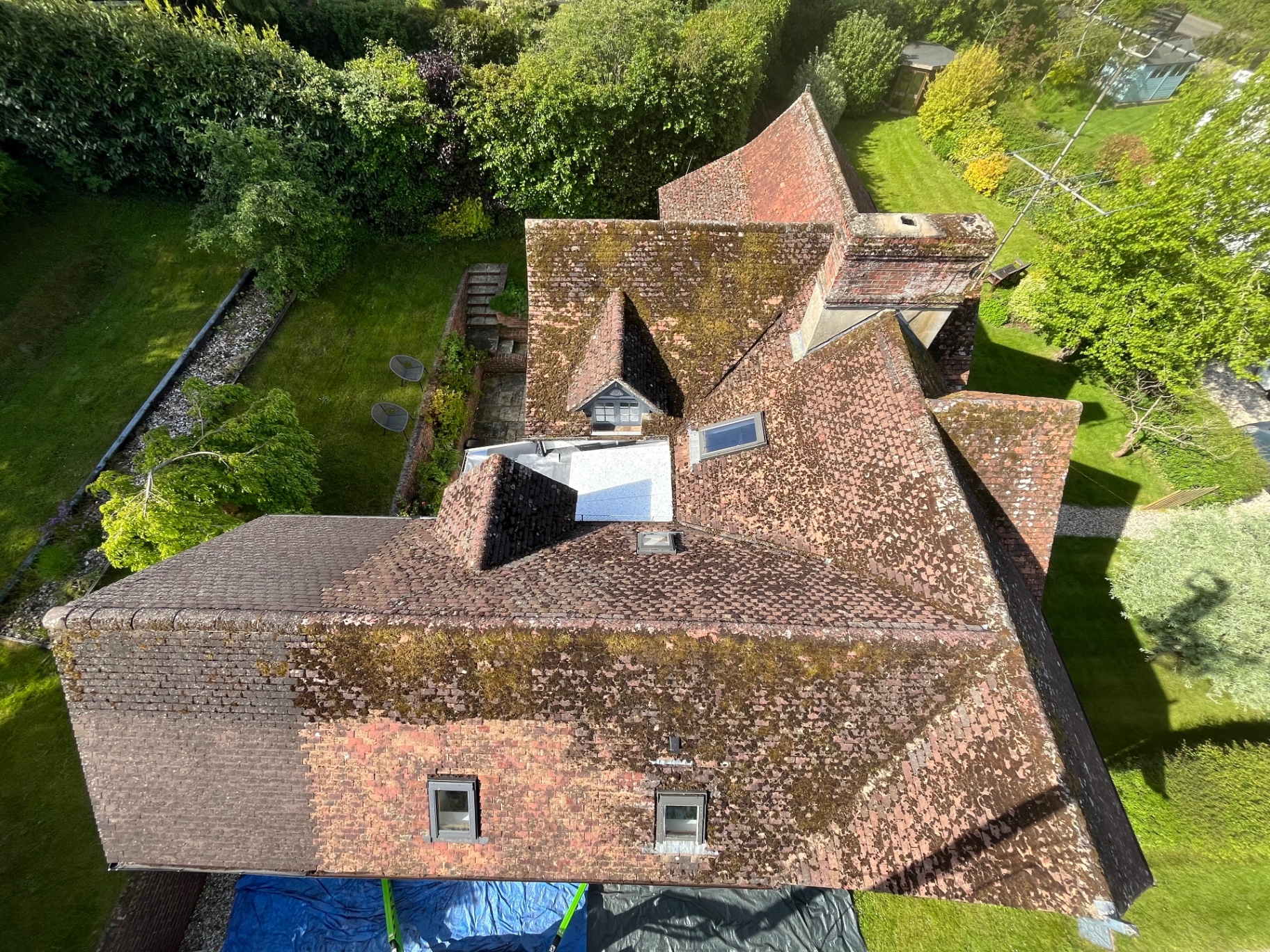 Aerial view of a tiled roof covered in moss before cleaning