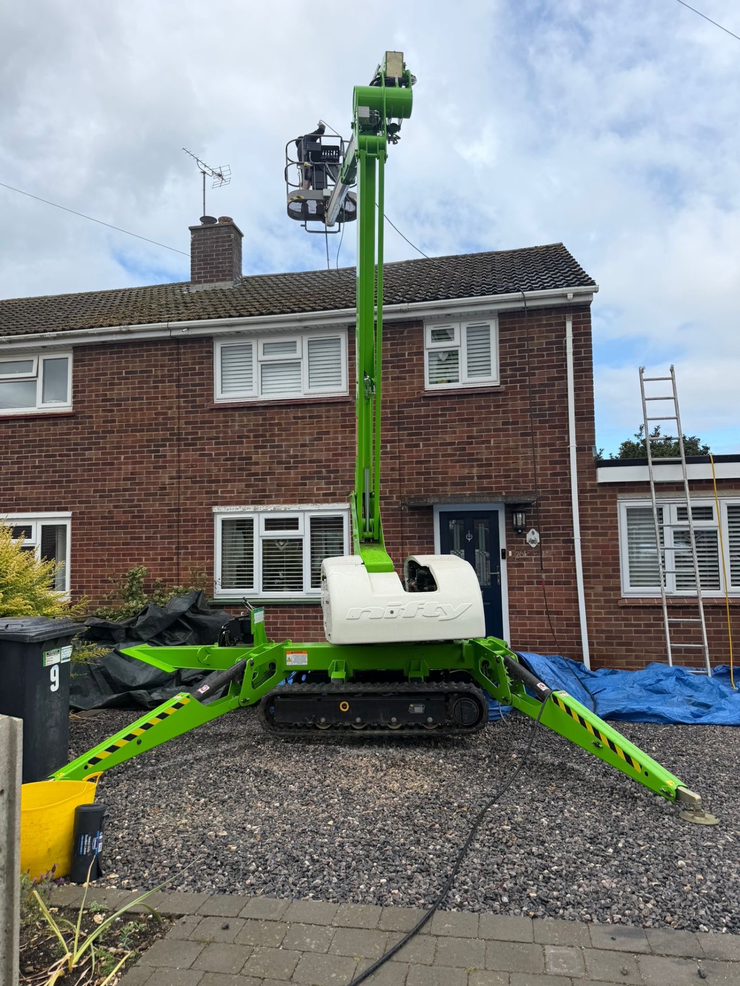 Tracked access platform positioned outside a home for roof cleaning